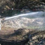 Boeing worker shoots a load of water over the debris field to keep asbestos dust down.