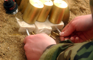 Inserting blasting caps into blocks of C-4 plastic explosive